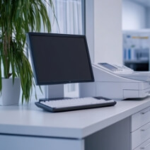 オフィスデスクに置かれたパソコンと複合機