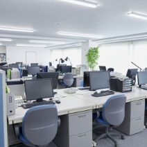 広いオフィスにデスクとパソコンが並ぶ風景